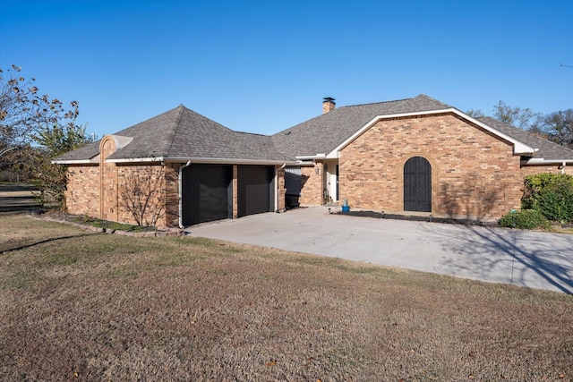 view of front facade with a garage, driveway, a chimney, and brick siding