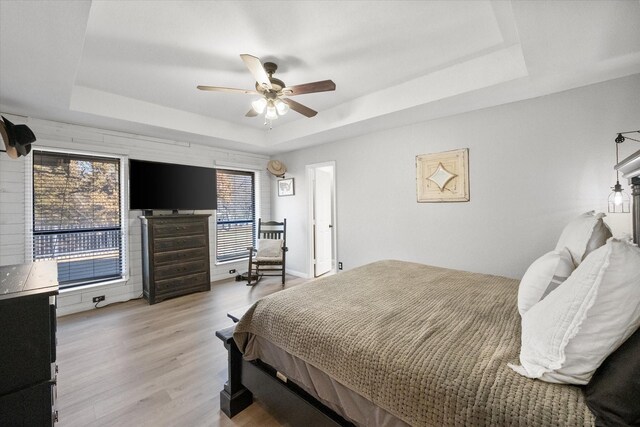 bedroom with a tray ceiling, ceiling fan, and light wood-type flooring