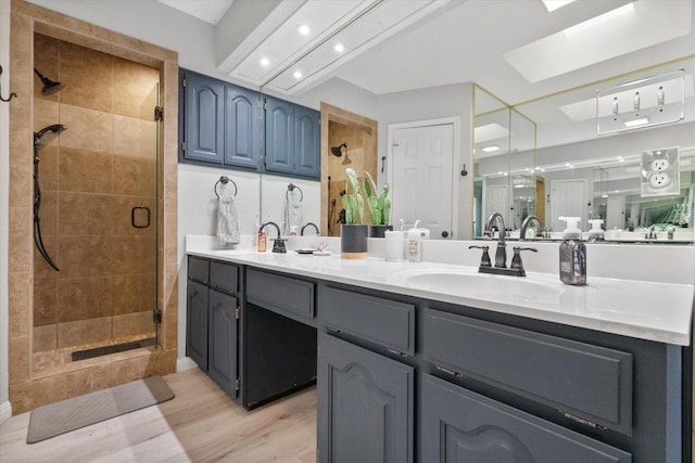 bathroom with wood-type flooring, vanity, a skylight, and a shower with shower door