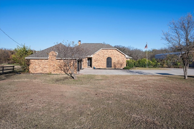 view of front facade with brick siding, a front yard, and fence