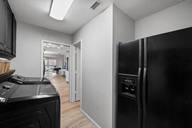 clothes washing area with cabinets, washing machine and dryer, and light hardwood / wood-style floors