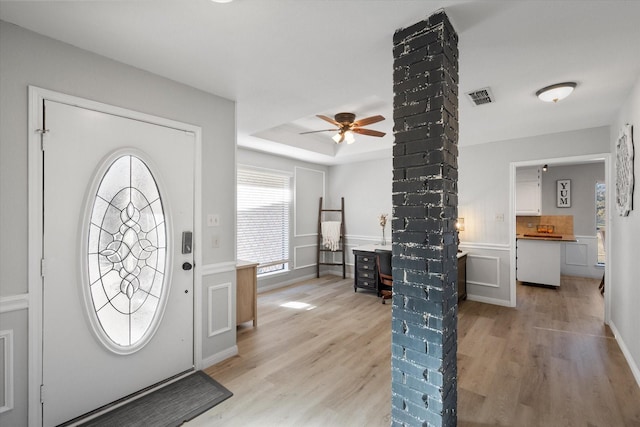 entryway with a raised ceiling, ceiling fan, and light hardwood / wood-style flooring