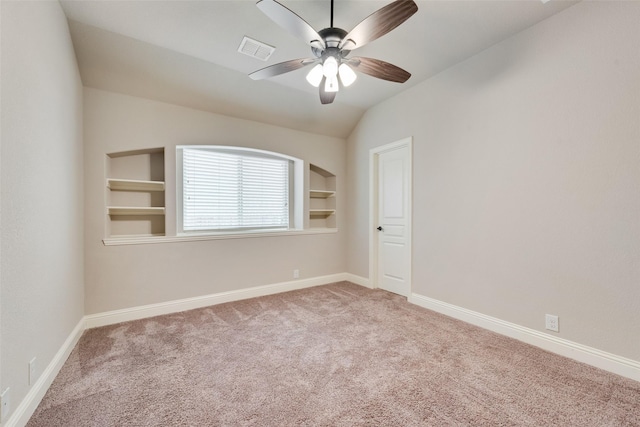 carpeted spare room featuring vaulted ceiling, built in features, and ceiling fan