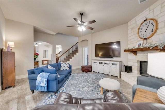 living room featuring ceiling fan, light wood-type flooring, and a fireplace