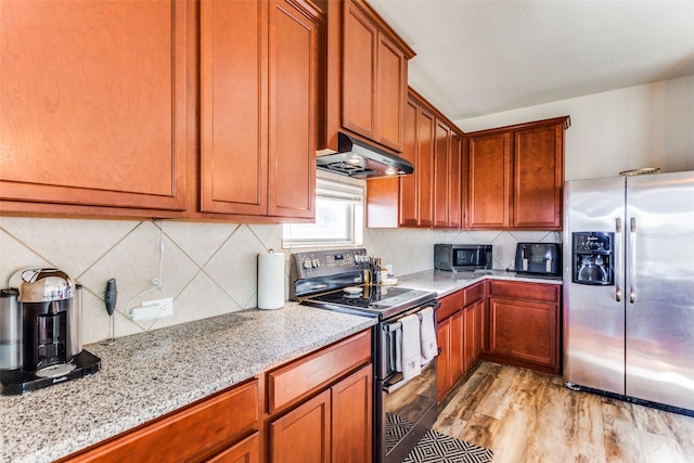 kitchen with light stone counters, extractor fan, light wood-type flooring, and appliances with stainless steel finishes