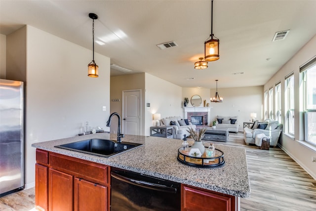 kitchen featuring dishwasher, sink, stainless steel fridge, a fireplace, and light wood-type flooring