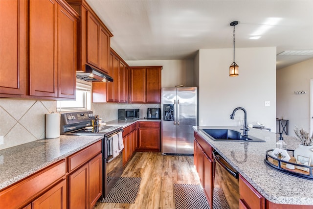 kitchen with sink, hanging light fixtures, light hardwood / wood-style flooring, black appliances, and exhaust hood