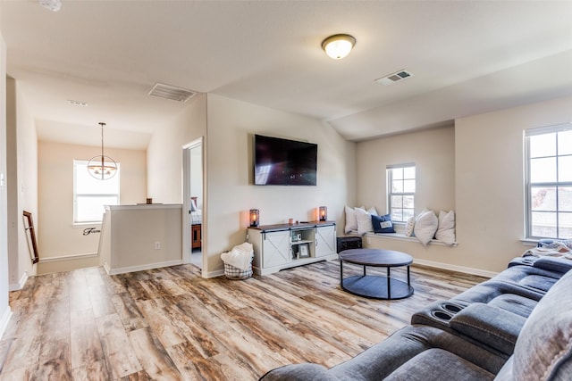 living room with a notable chandelier, lofted ceiling, and light hardwood / wood-style flooring