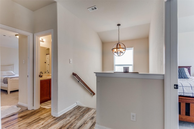 staircase featuring hardwood / wood-style floors, lofted ceiling, sink, and an inviting chandelier