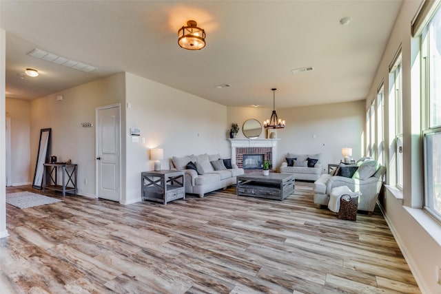 living room featuring a fireplace, light wood-type flooring, and a chandelier