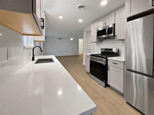 kitchen featuring light wood-type flooring, stainless steel appliances, sink, and white cabinets