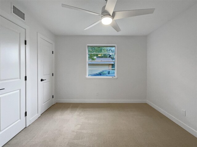 empty room with ceiling fan and light carpet