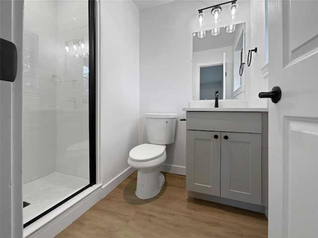 bathroom featuring toilet, a tile shower, wood-type flooring, and vanity