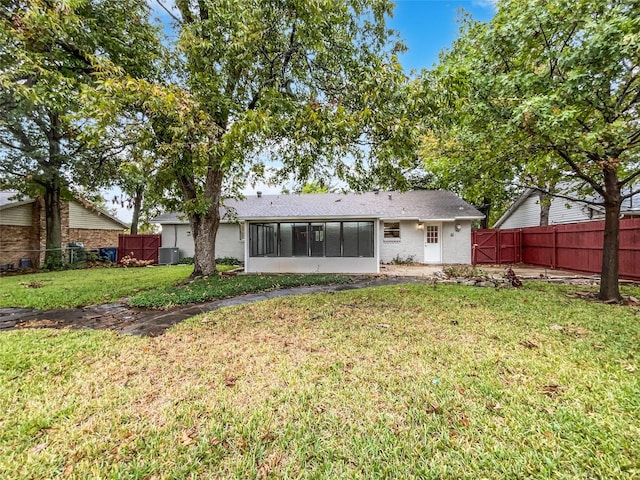 back of property with a lawn and a sunroom