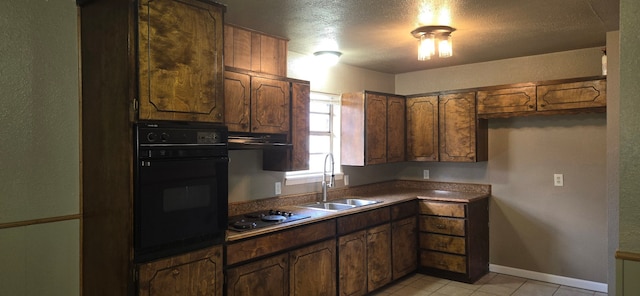 kitchen with sink, gas stovetop, oven, a textured ceiling, and light tile patterned flooring