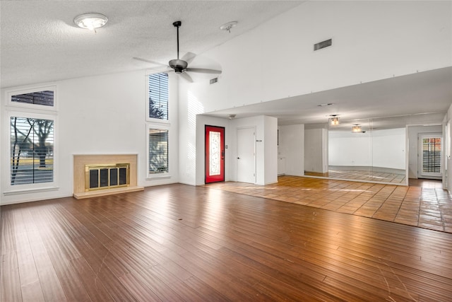 unfurnished living room with ceiling fan, high vaulted ceiling, hardwood / wood-style floors, and a textured ceiling