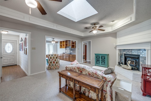 living room with a textured ceiling, a skylight, a wealth of natural light, and a tray ceiling