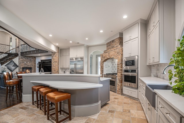 kitchen with white cabinetry, a kitchen breakfast bar, decorative backsplash, a center island, and built in appliances