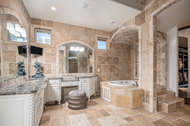 bathroom with independent shower and bath, vanity, and tile walls