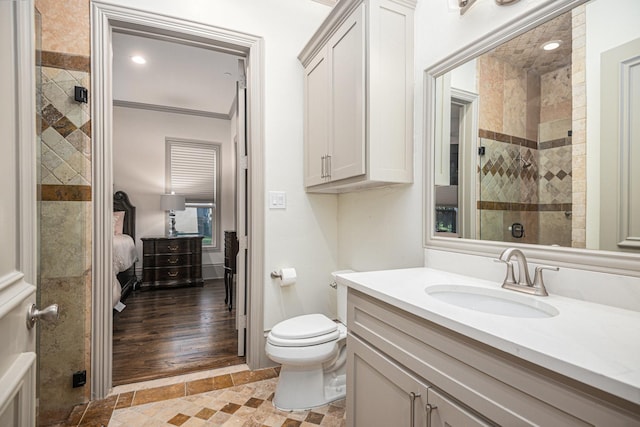 bathroom featuring vanity, tiled shower, ornamental molding, and toilet