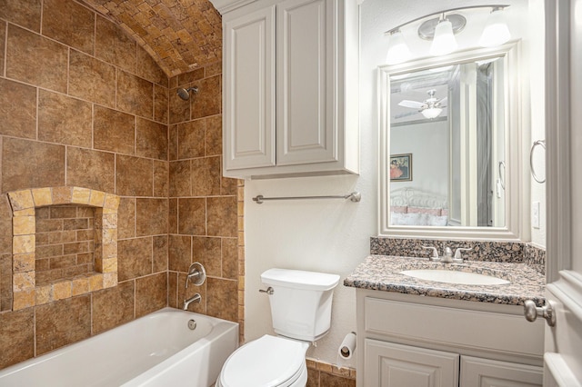 full bathroom featuring vanity, tiled shower / bath, and toilet