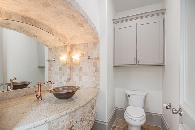 bathroom with sink, brick ceiling, and toilet