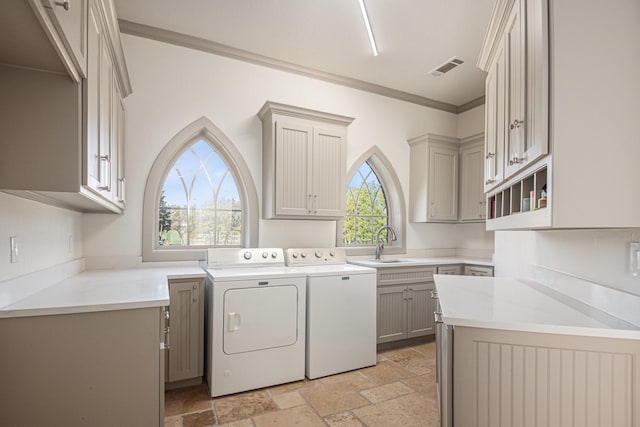 washroom featuring cabinets, ornamental molding, sink, and washer and clothes dryer