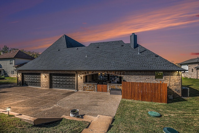 view of front of house featuring a garage, central AC, and a lawn