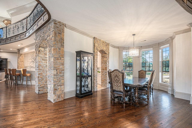 dining room featuring dark wood-type flooring, ornamental molding, and decorative columns