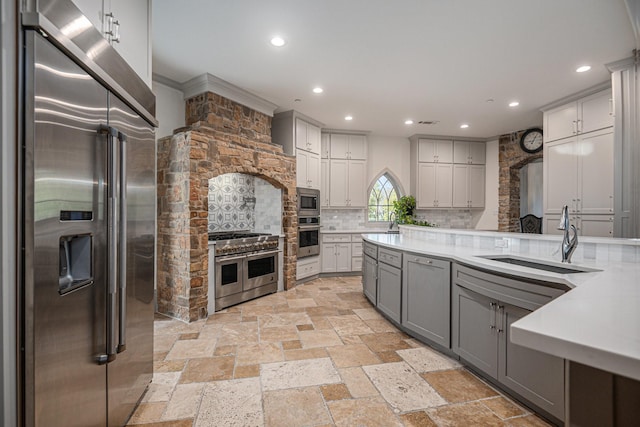 kitchen with gray cabinetry, built in appliances, and backsplash