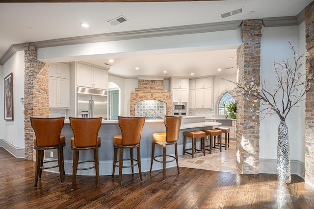 1714 Maranatha Way, Southlake, TX 76092 - kitchen with built in appliances, ornamental molding, dark wood finished floors, tasteful backsplash, and a breakfast bar