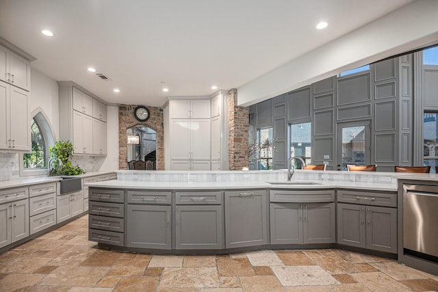 kitchen with sink, backsplash, gray cabinets, and stainless steel dishwasher