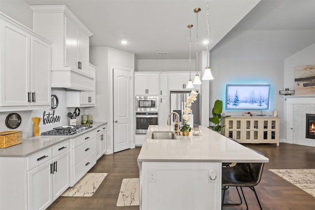 kitchen featuring white cabinets, pendant lighting, an island with sink, and stainless steel appliances