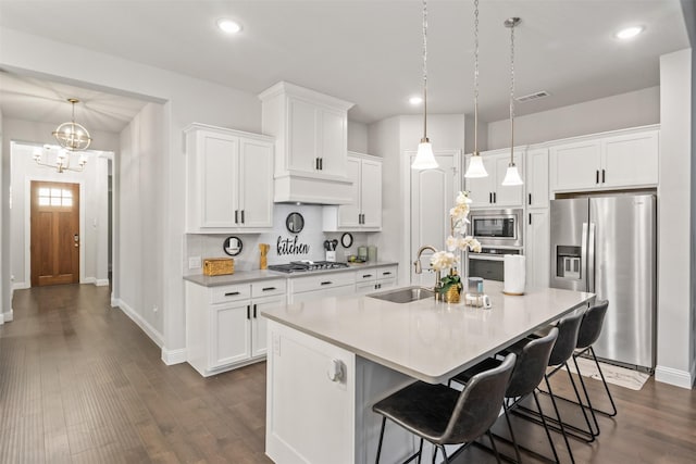 kitchen with pendant lighting, sink, dark hardwood / wood-style floors, appliances with stainless steel finishes, and white cabinetry