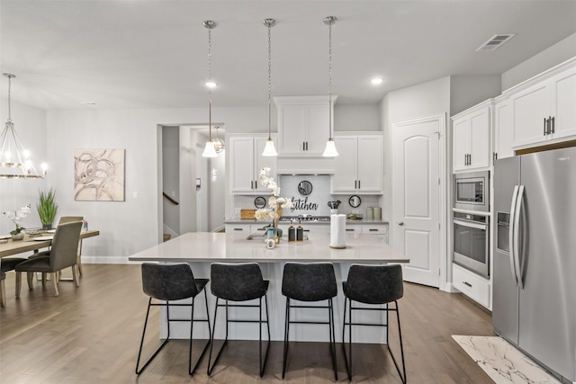 kitchen with pendant lighting, white cabinetry, an island with sink, and appliances with stainless steel finishes