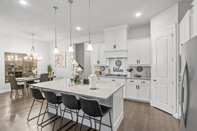 kitchen featuring premium range hood, decorative light fixtures, dark hardwood / wood-style flooring, white cabinetry, and stainless steel appliances