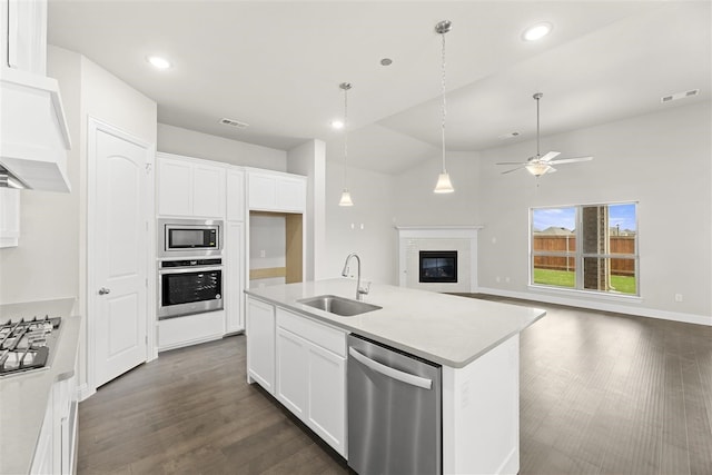 kitchen with white cabinets, stainless steel appliances, a kitchen island with sink, and sink