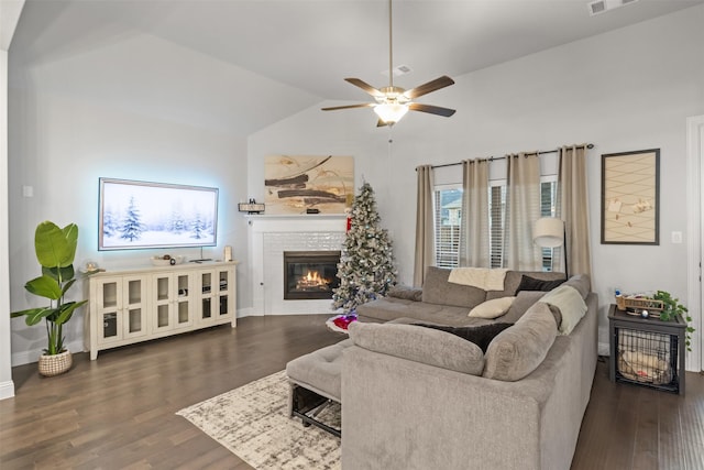 living room featuring a stone fireplace, ceiling fan, dark hardwood / wood-style flooring, and vaulted ceiling