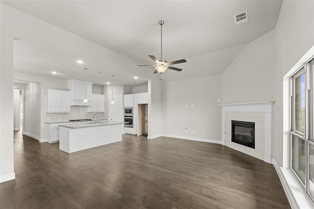 unfurnished living room with a fireplace, dark hardwood / wood-style flooring, ceiling fan, and sink