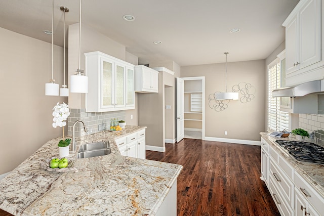 kitchen featuring white cabinets, backsplash, hanging light fixtures, and sink