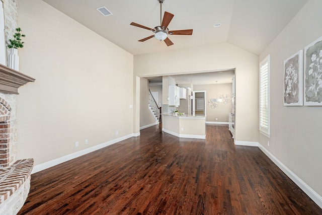 unfurnished living room with vaulted ceiling, ceiling fan, dark hardwood / wood-style floors, and a brick fireplace