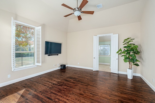 unfurnished living room featuring dark hardwood / wood-style flooring, vaulted ceiling, a wealth of natural light, and ceiling fan