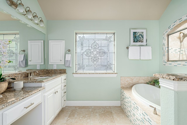 bathroom featuring vanity, a relaxing tiled tub, tile patterned floors, and a wealth of natural light