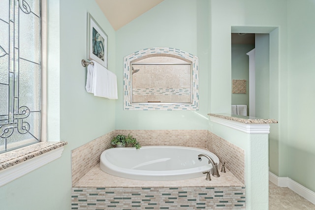 bathroom featuring tiled bath and vaulted ceiling