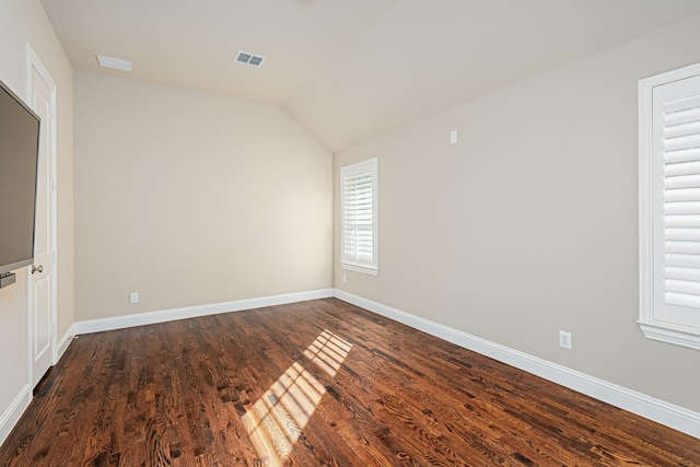 spare room featuring dark hardwood / wood-style flooring and lofted ceiling