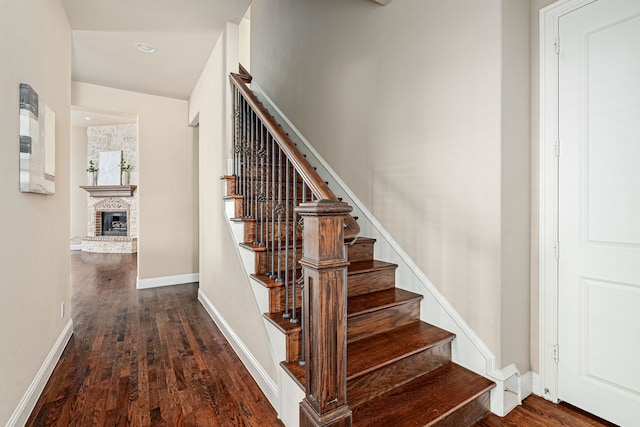 stairway with hardwood / wood-style floors and a brick fireplace