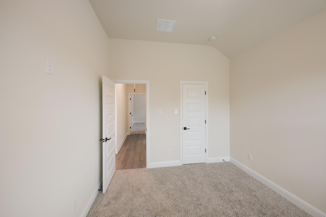 unfurnished bedroom featuring carpet and vaulted ceiling