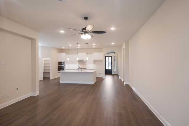 unfurnished living room featuring dark hardwood / wood-style floors, ceiling fan, and sink