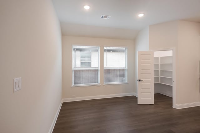 unfurnished bedroom with a walk in closet, dark hardwood / wood-style floors, vaulted ceiling, and a closet