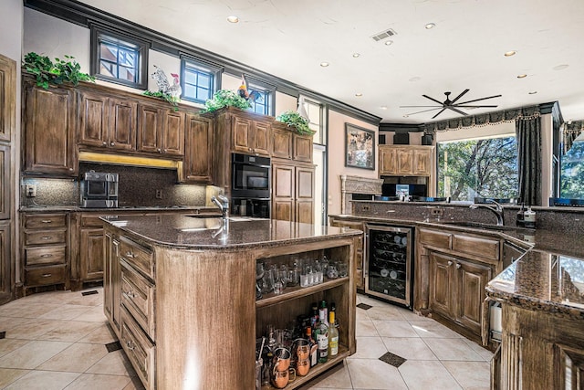 kitchen featuring an island with sink, sink, a wealth of natural light, and wine cooler